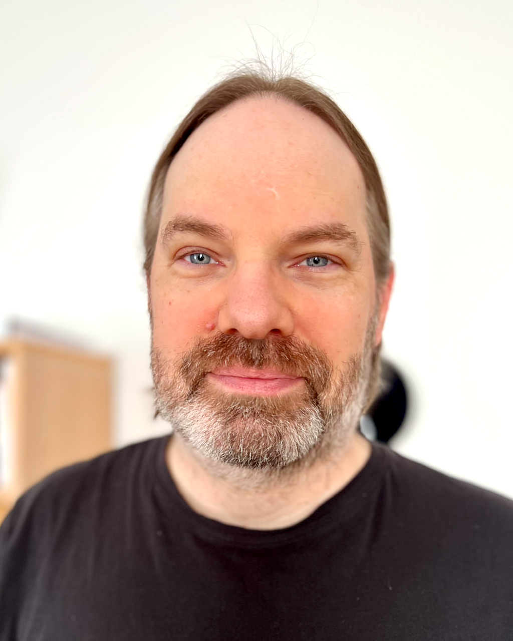 David Hagman in a black t-shirt standing in his home.